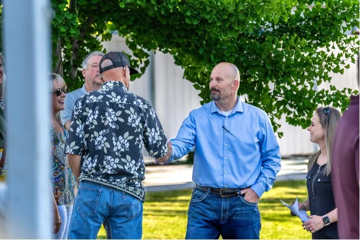 Chris Lee shaking hands with supporters at an outdoor community event
