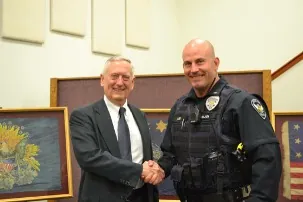 Chris Lee in police uniform shaking hands at a ceremony